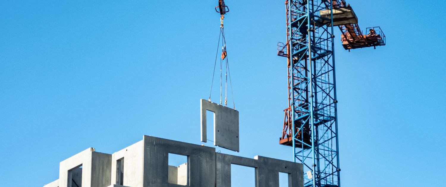 Tower crane delivers a concrete slab at a construction site