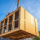 Wooden building module is raised by a crane and placed into the framework